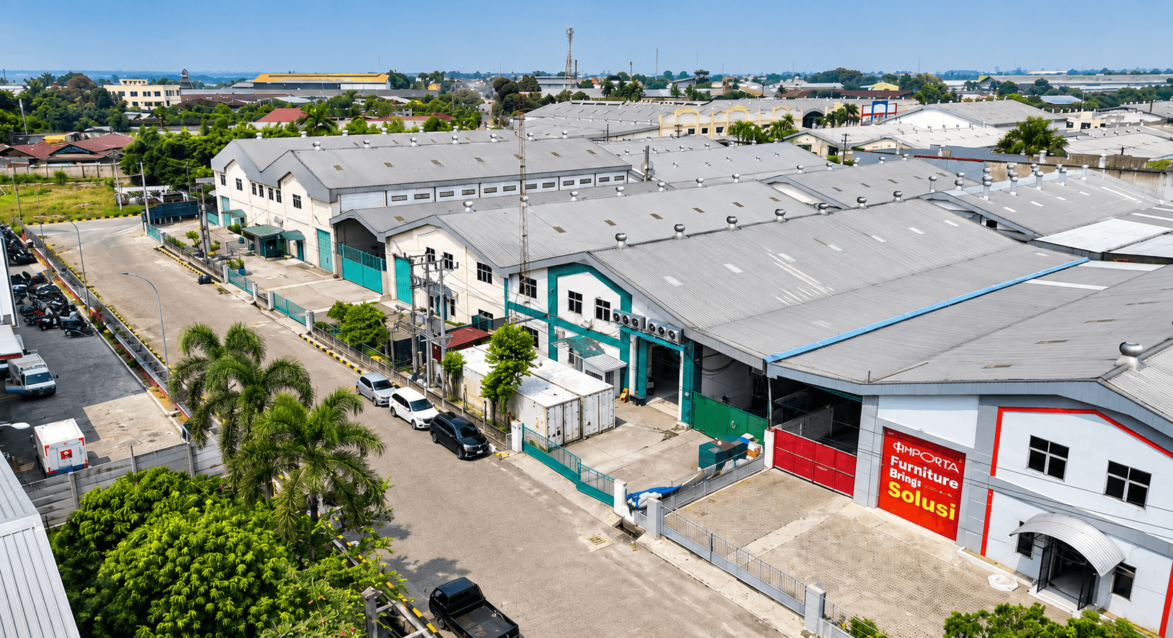 Aerial view of an industrial warehouse complex with light-colored roofs and surrounding streets.